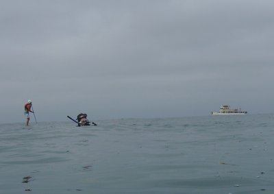 A paddle boarder, two divers and a fishing boat.